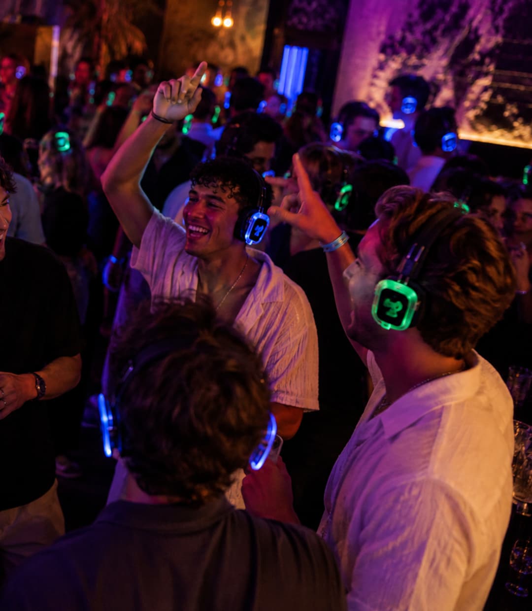 Vrienden dansen en zingen mee. Hun koptelefoons lichten blauw op.